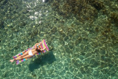 Yukarıdan aşağıya bir hava yatağı üzerinde yüzen bir güzel kadının beyaz bir bikini görünümü 