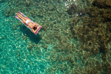 Yukarıdan aşağıya bir hava yatağı üzerinde yüzen bir güzel kadının beyaz bir bikini görünümü 