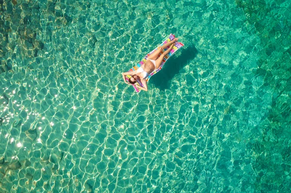 Yukarıdan aşağıya bir hava yatağı üzerinde yüzen bir güzel kadının beyaz bir bikini görünümü 