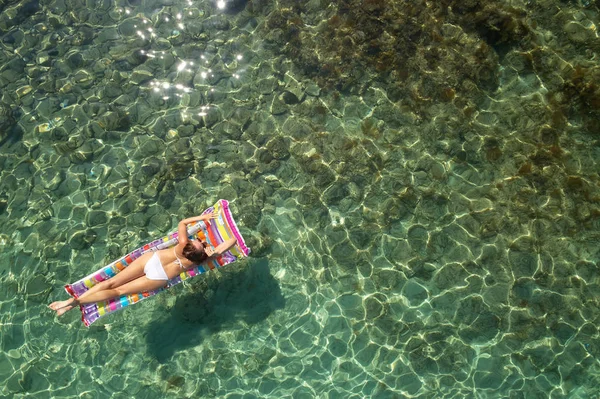 Yukarıdan aşağıya bir hava yatağı üzerinde yüzen bir güzel kadının beyaz bir bikini görünümü 