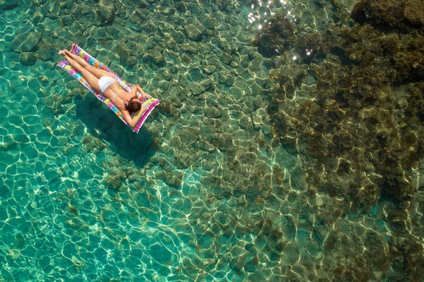 Yukarıdan aşağıya bir hava yatağı üzerinde yüzen bir güzel kadının beyaz bir bikini görünümü 