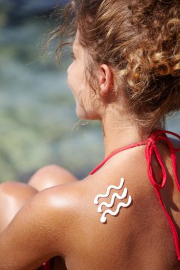 Woman with suntan lotion at the beach in form of a waves clipart