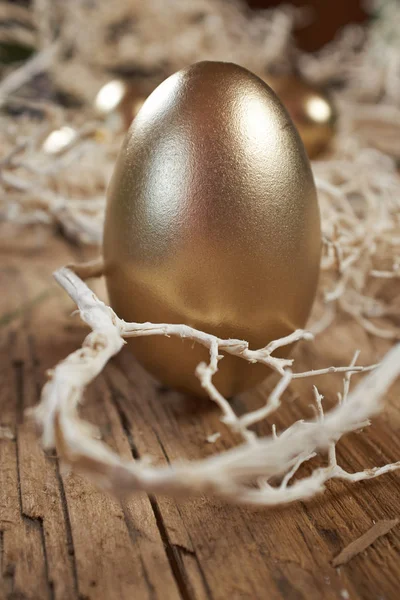 Golden easter eggs in nest on vintage rustic wooden background — Stock Photo, Image