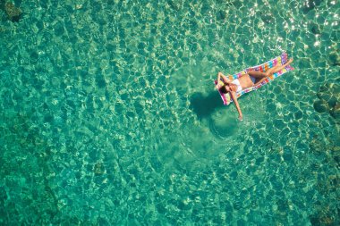 Yukarıdan aşağıya bir hava yatağı üzerinde yüzen bir güzel kadının beyaz bir bikini görünümü 