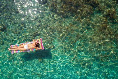 Yukarıdan aşağıya bir hava yatağı üzerinde yüzen bir güzel kadının beyaz bir bikini görünümü 
