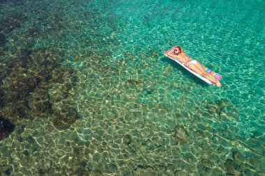 Yukarıdan aşağıya bir hava yatağı üzerinde yüzen bir güzel kadının beyaz bir bikini görünümü 