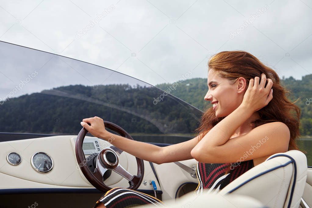 Summer vacation - young woman driving a motor boat 