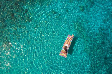 Denizde bir yatak üzerinde bikini güzel bir genç kadının havadan görünümü 