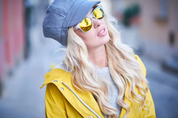 Blond meisje in een gele regenjas — Stockfoto