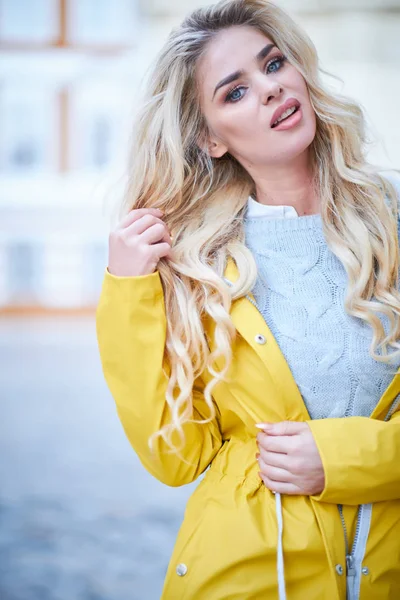 Blondes Mädchen im gelben Regenmantel — Stockfoto