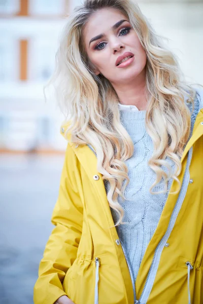 Blond meisje in een gele regenjas — Stockfoto