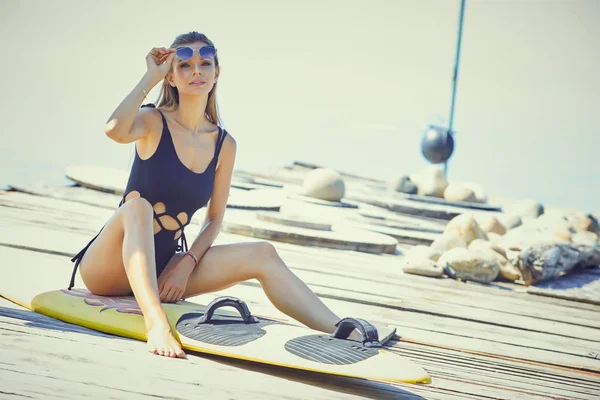 Junge Frau im Neoprenanzug mit Surfbrett stehend — Stockfoto