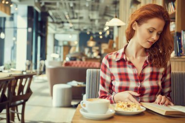 Kırmızı saçlı kadın Cafe kitap okumak. Şehir sonu kavramı