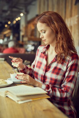 Kırmızı saçlı kadın Cafe kitap okumak. Şehir sonu kavramı