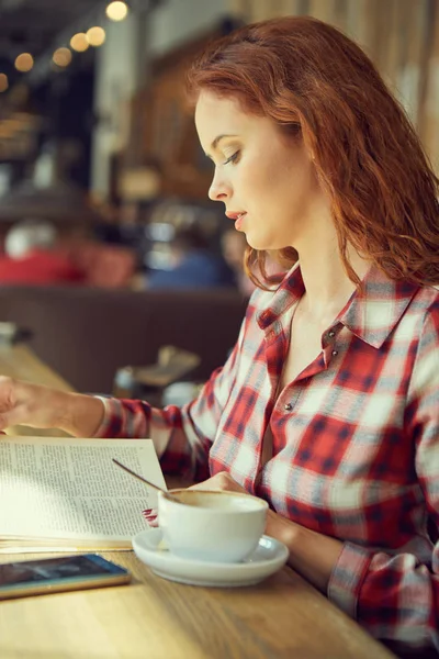 Femme rousse lisant un livre au café. Concept de City break — Photo