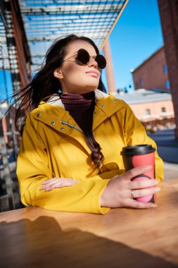 Kız sokakta bir kafede kahve içiyor.