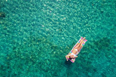 Yukarıdan aşağıya bir hava yatağı üzerinde yüzen bir güzel kadının beyaz bir bikini görünümü