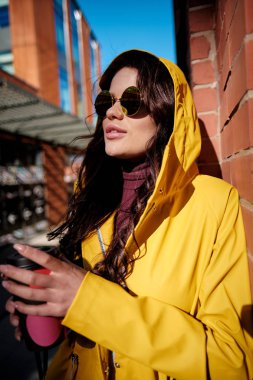 Kahve üstünde belgili tanımlık gitmek. Kahve fincanı tutarak ve cadde boyunca yürürken gülümseyen güzel genç kadın 