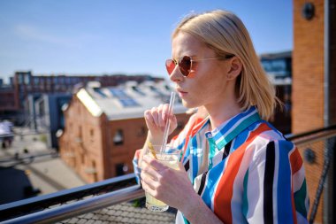 Kız çatı barda bir kokteyl içiyor