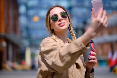 Bahar tatilinde genç ve mutlu bir bayan, şehirde yürüyor, içki içiyor.