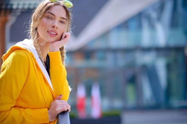 Hermosa mujer en una sudadera amarilla y gafas de sol en el st — Foto de Stock