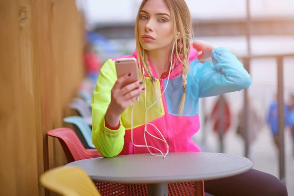 Young female runner is having break and listening to music durin — Stock Photo, Image