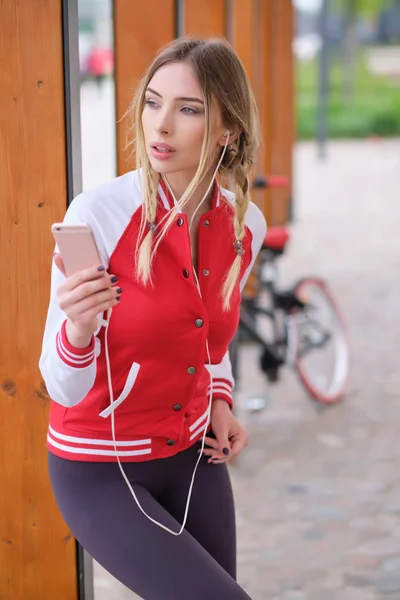 Moda jovem bonita ouve música usando o smartphone nea — Fotografia de Stock