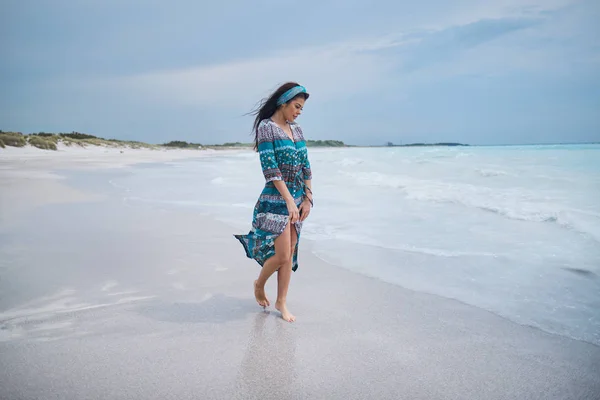 Женщина в красивом платье. гуляя по пляжу и глядя на — стоковое фото