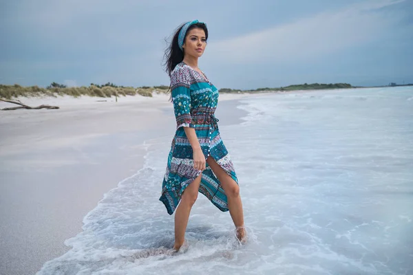 Kvinna i den vackra klänningen. promenader på stranden och ser en — Stockfoto