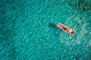 Denizde bir yatak üzerinde bikini güzel bir genç kadının havadan görünümü 