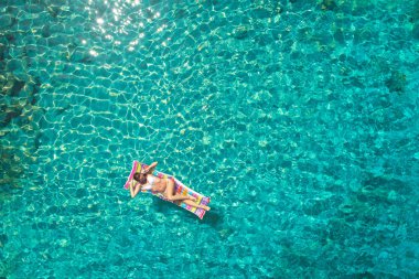 Denizde bir yatak üzerinde bikini güzel bir genç kadının havadan görünümü 