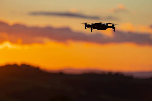 Flying silhouette of drone against sunset. Flying silhouette of drone against beautiful sunset sky