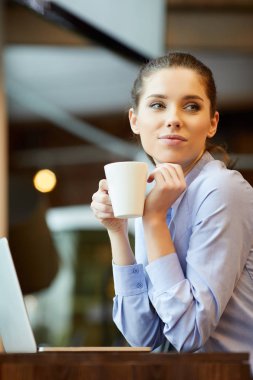 İyi günler! Genç güzel kadın kahve fincanı tutan ve oturan bir