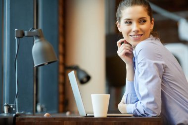 İyi günler! Genç güzel kadın kahve fincanı tutan ve oturan bir