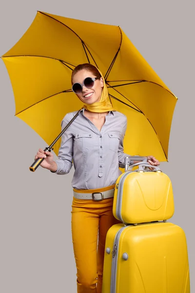 Glamour-Frau unter gelbem Regenschirm und Koffer — Stockfoto