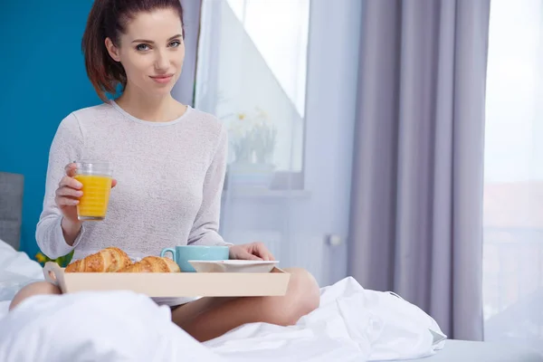 Donna attraente mangiare cereali seduto sul letto a casa — Foto Stock