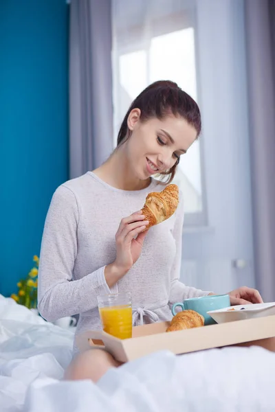 Donna attraente mangiare cereali seduto sul letto a casa — Foto Stock