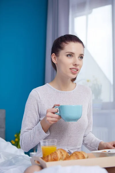 Donna attraente mangiare cereali seduto sul letto a casa — Foto Stock