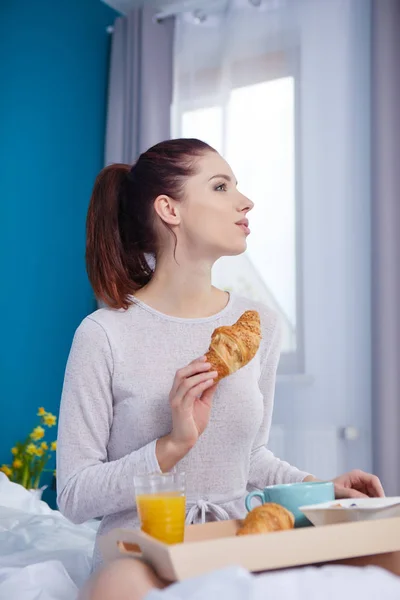 Attraktiv kvinna äta spannmål sitter på sängen hemma — Stockfoto