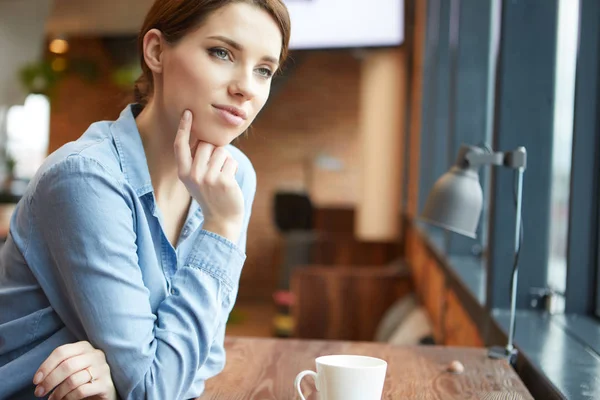 En ung kvinna som dricker kaffe på kontoret — Stockfoto