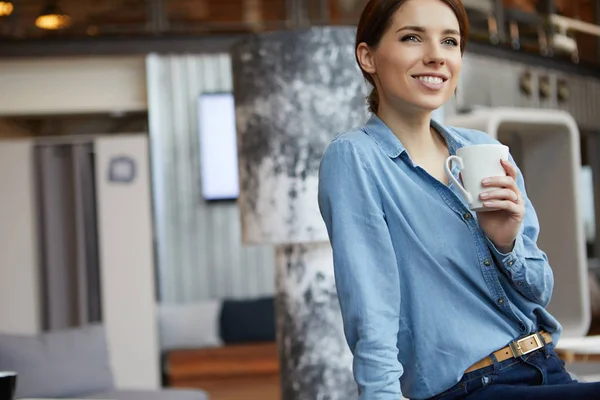 Een jonge vrouw die koffie drinkt op kantoor — Stockfoto