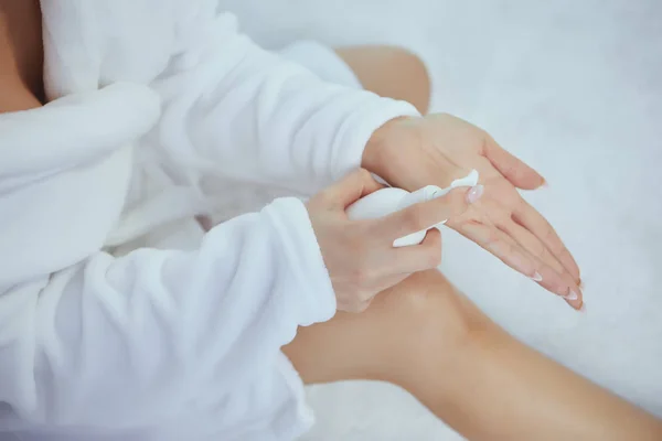 Imagen recortada de la hermosa joven aplicación de crema de manos mientras — Foto de Stock