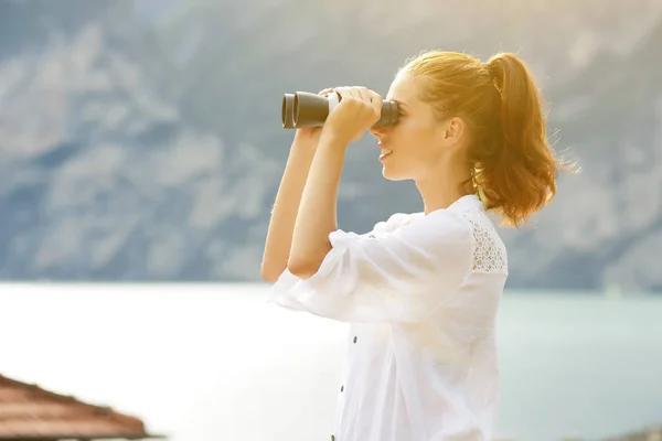 Mujer turista en la cima de la montaña mirando a través de prismáticos —  Fotos de Stock