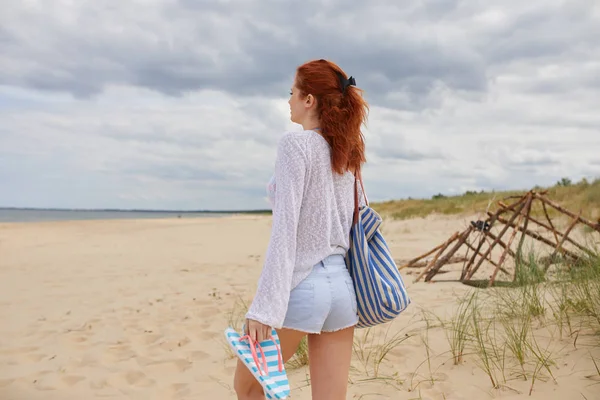 En kvinne som går på stranden. Kvinner som har fritid går barfotet – stockfoto