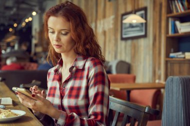 Kız bir kafede kahve içip kitap okuyor.