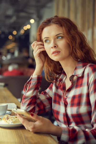 Het meisje drinkt koffie in een café en leest een boek — Stockfoto