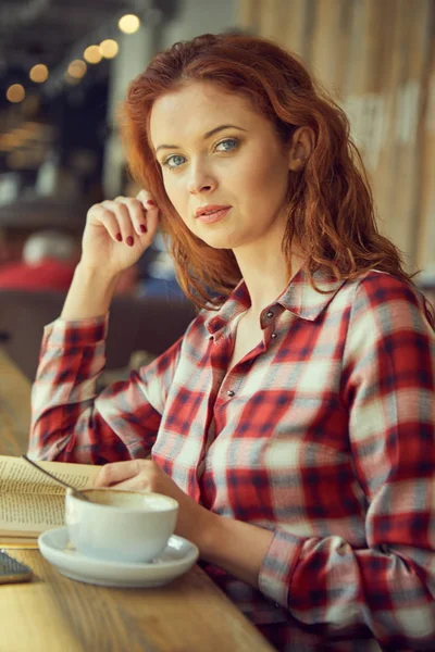 Das Mädchen trinkt Kaffee in einem Café und liest ein Buch — Stockfoto