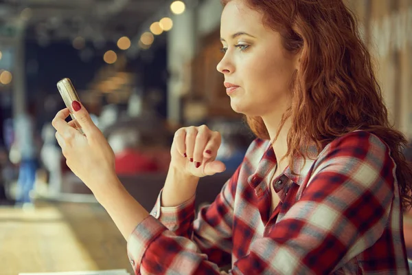 La ragazza sta bevendo caffè in un caffè e leggendo un libro — Foto Stock