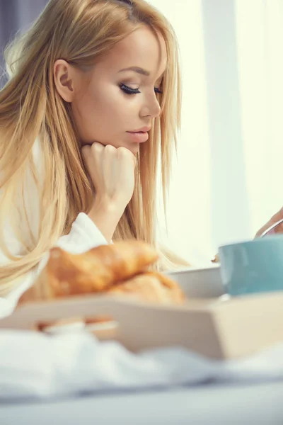 Ung vacker kvinna äter frukost i sängen. — Stockfoto