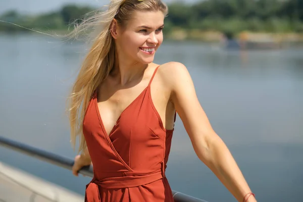 Schöne Frau im roten Kleid. Hintergrund des Stadtflusses. — Stockfoto